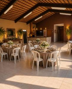 a dining room with tables and white chairs at Recanto sonho meu in Trindade