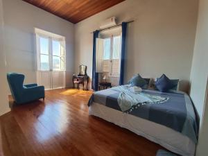 a bedroom with a bed and a chair and windows at Guesthouse Villa Dourada in Rio de Janeiro