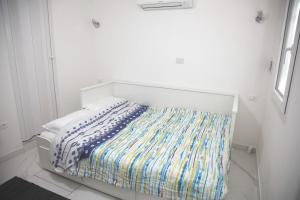 a white bedroom with a bed with a colorful blanket at Ama affittacamere in Gleris