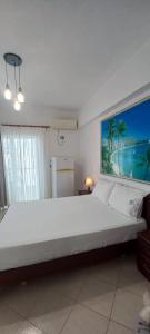 a bedroom with a large white bed with a large painting on the wall at Vila Ester in Ksamil