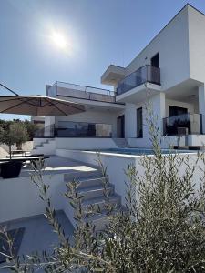a large white house with a patio and an umbrella at Villa Omorfia - SEVID in Sevid