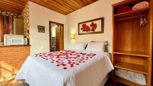 a bedroom with a bed with red flowers on it at Pousada Florada do Amanhã in Monte Verde