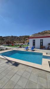 a swimming pool with two chairs next to a building at Noor-Hatta Deluxe Villa Farmhouse in Hatta
