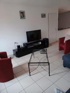 a living room with a flat screen tv and red chairs at Maison au calme in La Roche-sur-Yon