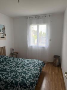 a bedroom with a bed with a green comforter and a window at Maison au calme in La Roche-sur-Yon