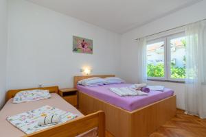 two beds in a room with a window at Apartments Ian in Lopar