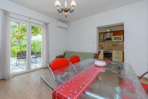 a dining room with a glass table and red chairs at Apartments Ian in Lopar