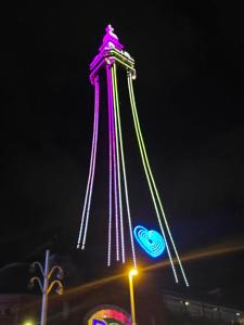 a tower lit up in pink and green at night at Northdene Theatre Hotel in Blackpool +5 photos