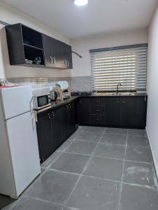 a kitchen with black cabinets and a white refrigerator at Ivaeli Apartment in Lagos +5 photos