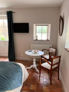 a bedroom with a table and chairs and a bed at La chambre des clefs in Ranville