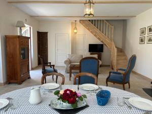 a living room with a table and chairs and a staircase at Maison Mélusine in Londigny
