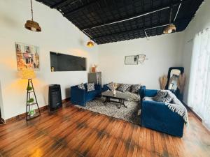 a living room with two blue couches and a flat screen tv at The cosmos farm in Gurgaon