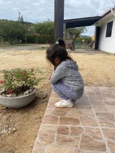 a little girl squatting next to a flower pot at Refugio para 2 in Santa Cruz