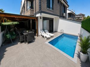 a patio with a pool and a table and chairs at Villa Ayla in Yukarı Kocaali