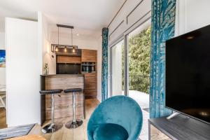 a living room with a blue chair and a television at Appartement Chic, Climatisation et Piscine in Ormoy-la-Rivière