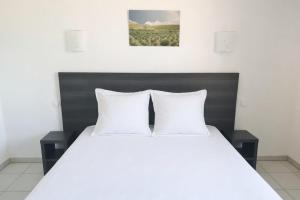 a white bed with two white pillows on it at Apparthotel Résidence La Provence in Istres