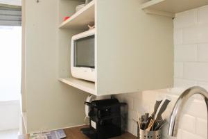 a microwave in a cabinet above a kitchen sink at Souplex - 4P - Batignolles in Paris +20 photos
