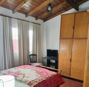 a bedroom with a bed and a cabinet and a television at El Quincho de Mariana in Balcarce