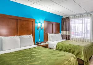 two beds in a hotel room with blue walls at Quality Inn East Stroudsburg - Poconos in East Stroudsburg