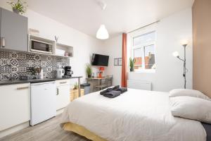 a white bedroom with a large bed and a kitchen at Studio plage - Séjours pros et vacances in Dunkerque