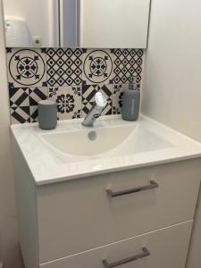 a bathroom sink with two cups and a mirror at Studio plage - Séjours pros et vacances in Dunkerque