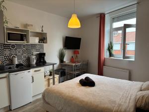 a bedroom with a bed and a kitchen with a counter at Studio plage - Séjours pros et vacances in Dunkerque