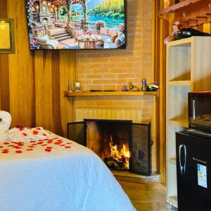 a bedroom with a fireplace with a tv above it at Pousada Florada do Amanhã in Monte Verde
