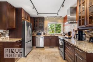 a kitchen with wooden cabinets and stainless steel appliances at Urban Oasis - with 16ft Swim Spa - Heated Hot Tub & Pool in Edmonton