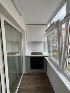 a small kitchen with white cabinets and a window at D&D Studio in Petrila +2 photos
