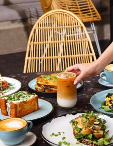 a table with plates of food and a person holding a drink at 23 Living in Medellín
