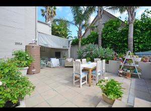 a patio with a table and chairs and palm trees at Skulpie in Cape Town