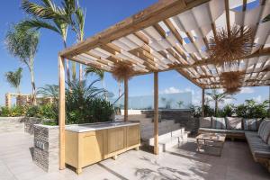a patio with a wooden pergola and a couch at Newport House Playa Boutique Hotel in Playa del Carmen