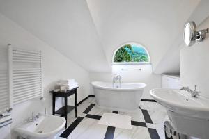 a white bathroom with two sinks and a tub at Brentano Elegante in Mezzegra