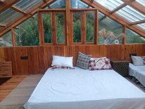 a large bed in a wooden room with windows at Cedar Forest BnB Villa in Kasol +6 photos