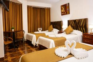 a hotel room with two beds with white swans on them at Villa Fernanda Hotel in Tacna