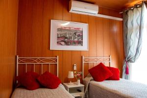 two beds with red pillows in a bedroom at La Cassola del Priorat in Gratallops