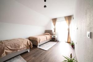 a white bedroom with two beds and a window at Koala Resort in Raška +19 photos