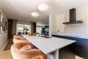 a kitchen with a large white counter with bar chairs at Villa Maya Rooftop beach access heated pool in Le Grau-dʼAgde