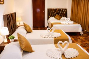 a hotel room with three beds with swans on them at Villa Fernanda Hotel in Tacna