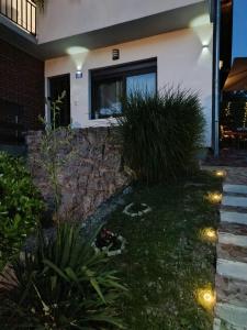 a house with a stone retaining wall and grass at Studio apartman EMA in Brodski Varoš +13 photos