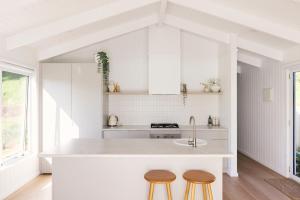 a kitchen with a white counter and two stools at Drift, Port Campbell in Port Campbell