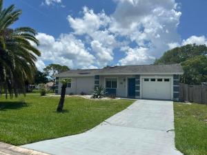 a house with a garage and a palm tree at Blue Beach Pool House in Port Orange