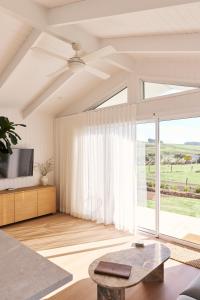 a living room with a table and a large window at Drift, Port Campbell in Port Campbell