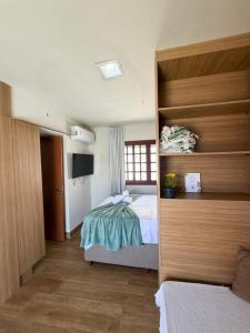 a bedroom with two beds and a television in it at Chalé Brisa da Mata Baia Formosa in Baía Formosa