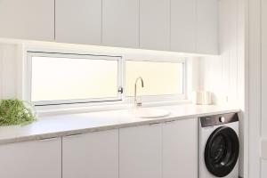 a white kitchen with a sink and a washing machine at Drift, Port Campbell in Port Campbell +42 photos