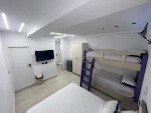 a room with two bunk beds and a flat screen tv at Ferra Hostel in Durrës