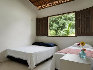 two beds in a room with a window at Refúgio na Serra à 15min do Centro in Crato