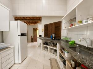 a white kitchen with a sink and a refrigerator at Refúgio na Serra à 15min do Centro in Crato