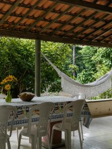 a table with chairs and a hammock on a patio at Refúgio na Serra à 15min do Centro in Crato