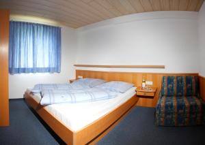 sypialnia z dużym łóżkiem i krzesłem w obiekcie Haus Muntschnei w mieście St. Gallenkirch